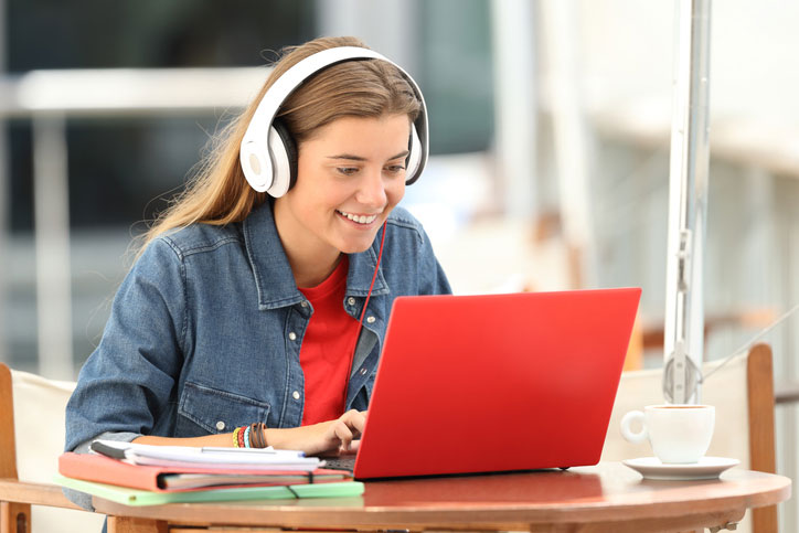 A young happy student with a head-set is learning English on her laptop.