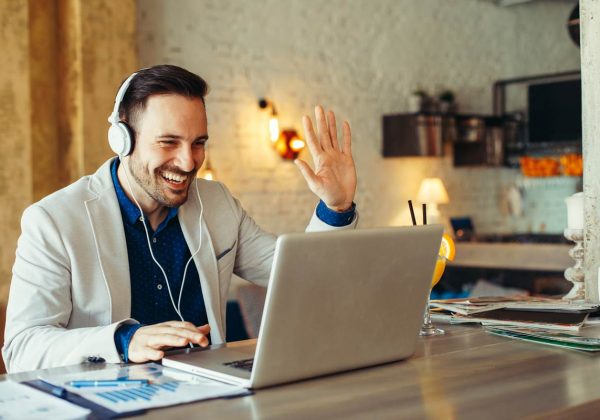 A man is learning English online via video conference an is waving at his teacher.