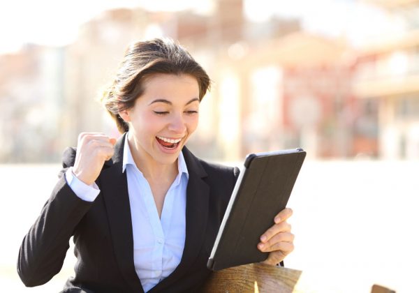 A business executive woman in an online video chat with her English teacher making a winner sign with her hand.