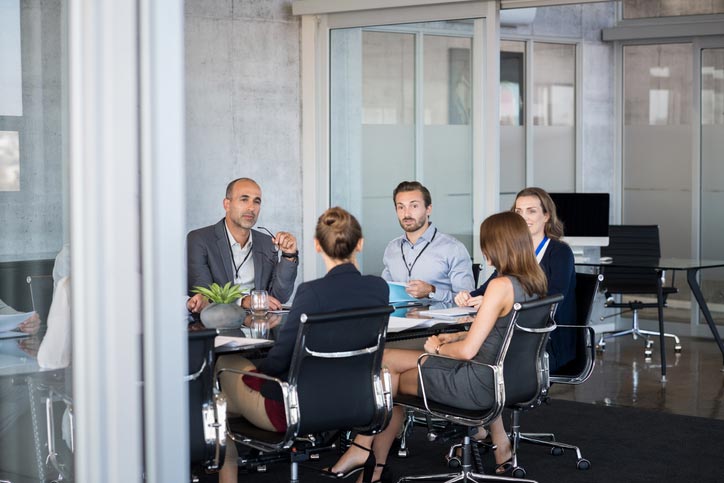 An Italian course in a company. The teacher and the participants are sitting around a table.