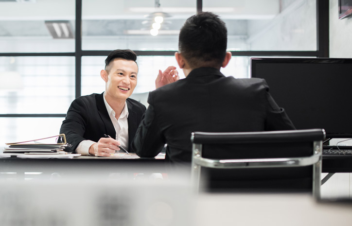 An employee is learning Chinese in a customised one to one language course in his company and is sitting at the table together with his Chinese teacher