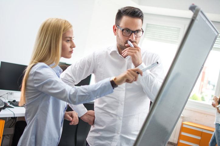 An employee is learning Swedish in a customised one-to-one language course in a company and is standing at the flipcharts together with the teacher - Photographer > getty images