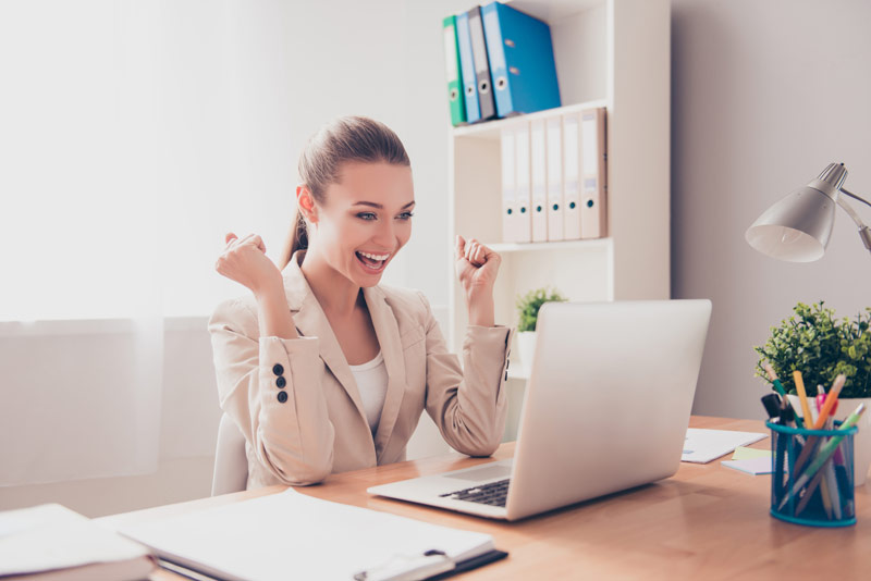 Business woman is sitting in her office cheering because she has passed her language exam