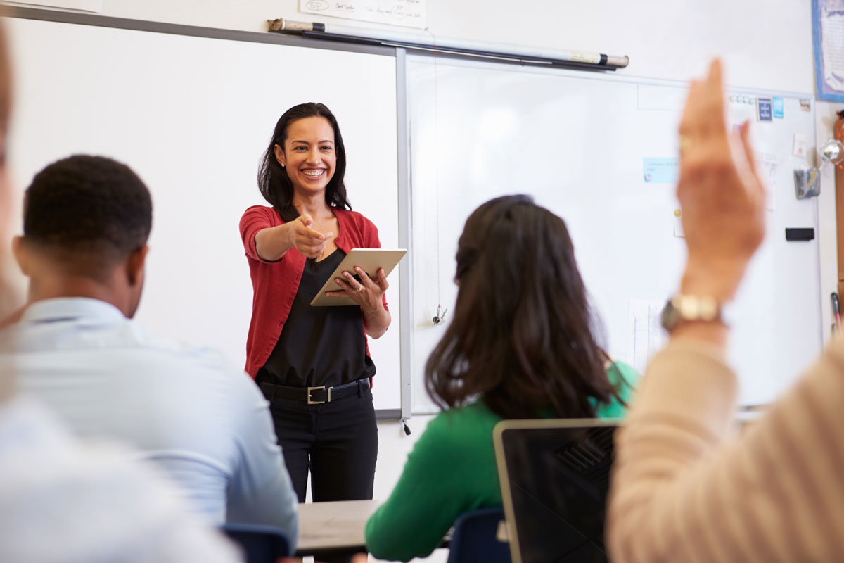 A Spanish course in a small group. The teacher is explaining at the flipchart facing and smiling at the students.