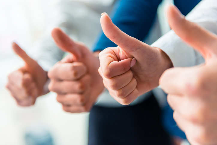 A group of employees in a company are pointing their thumbs up. - Photographer > getty images